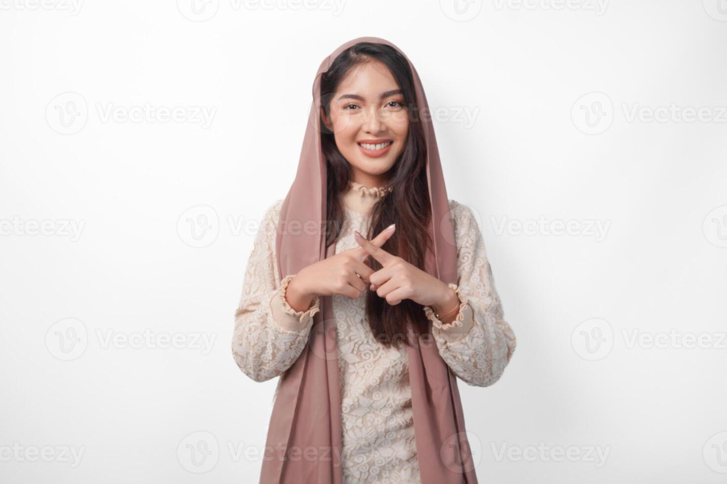 ung asiatisk muslim kvinna bär slöja hijab gestikulerar en Nej avslag, vägra använder sig av händer och fingrar, isolerat förbi vit bakgrund. ramadan och eid mubarak begrepp foto