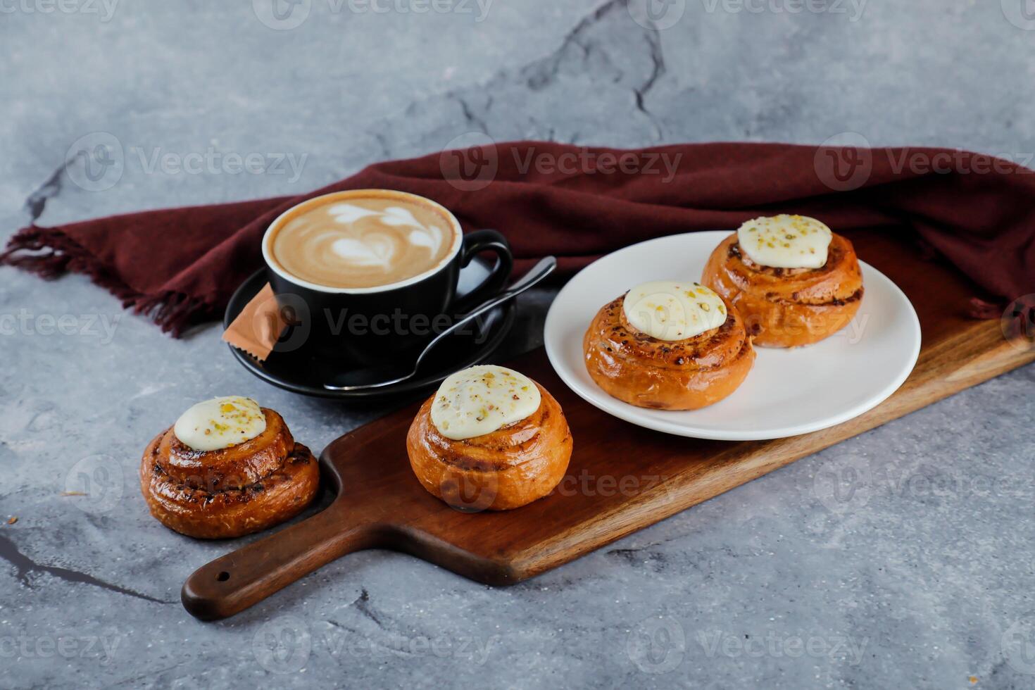 kanel rulla eras på trä- styrelse med kopp av kaffe latte konst isolerat på servett sida se av franska frukost bakad mat Artikel foto