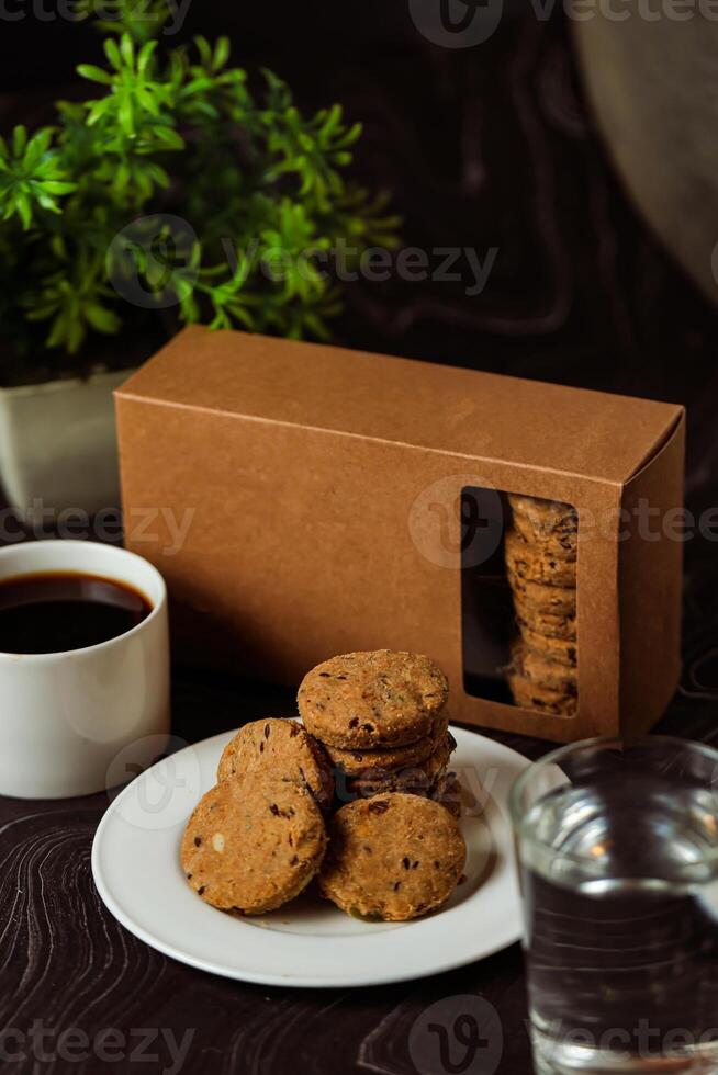 knaprig småkakor kex eras i tallrik med kaka låda, svart kaffe och glas av vatten isolerat på tabell sida se av amerikan Kafé bakad mat foto