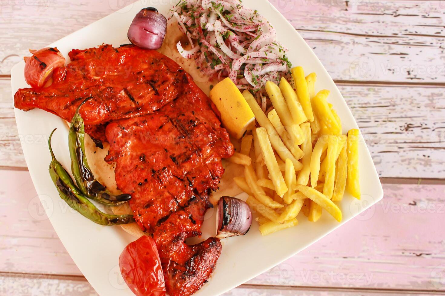 halv grillad tandoori kyckling med citron, lök och franska frites eras i maträtt isolerat trä- tabell topp se av tandoori grill bbq mat foto