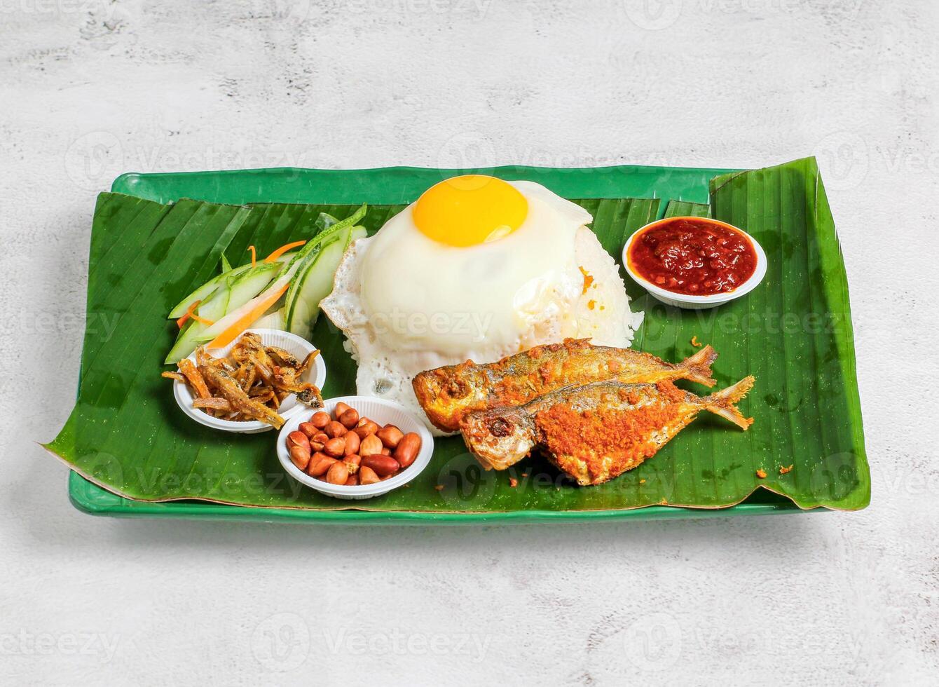 nasi lemak uppsättning med solig ägg, ris, friterad fisk, ättikslag, sallad, jordnöt och chili sås eras i maträtt isolerat på banan blad topp se av singapore mat foto