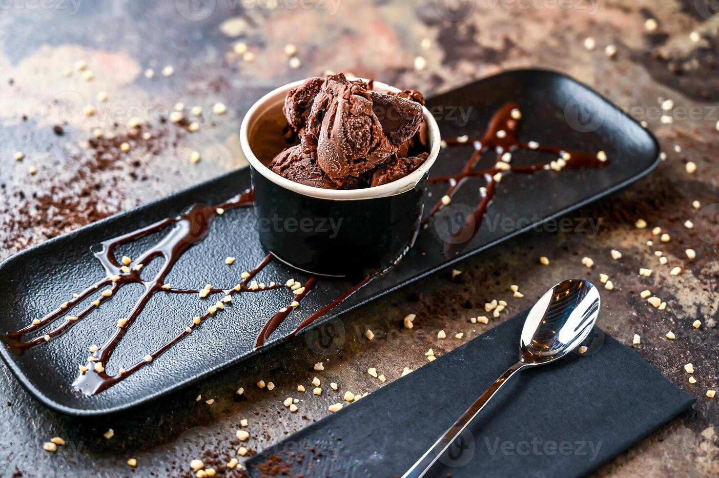 choklad gelato med is grädde, vit choklad chip, och sked eras i kopp isolerat på mörk bakgrund närbild topp se av Kafé bakad efterrätt mat foto