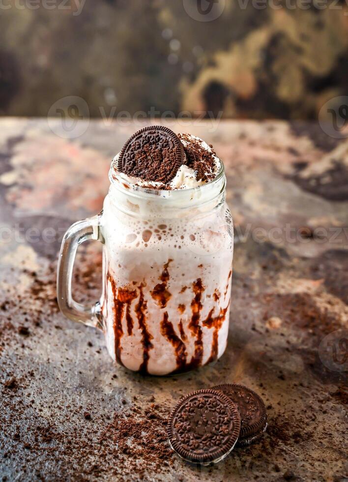 oreo milkshake med choklad och vispad grädde eras i burk isolerat på mörk bakgrund sida se av friska dryck foto