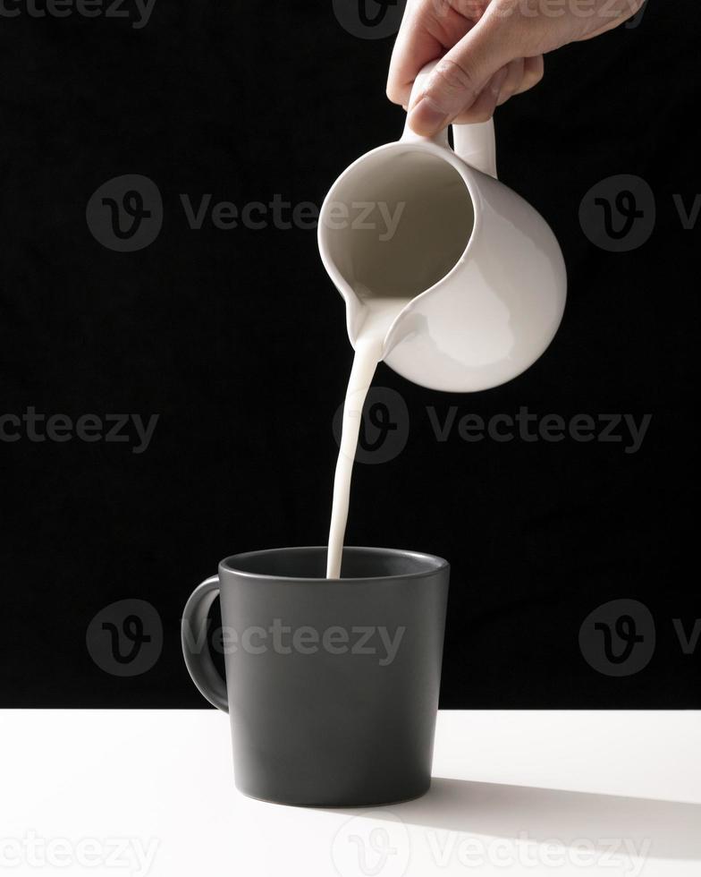 framifrån hand häller mjölk i mugg foto