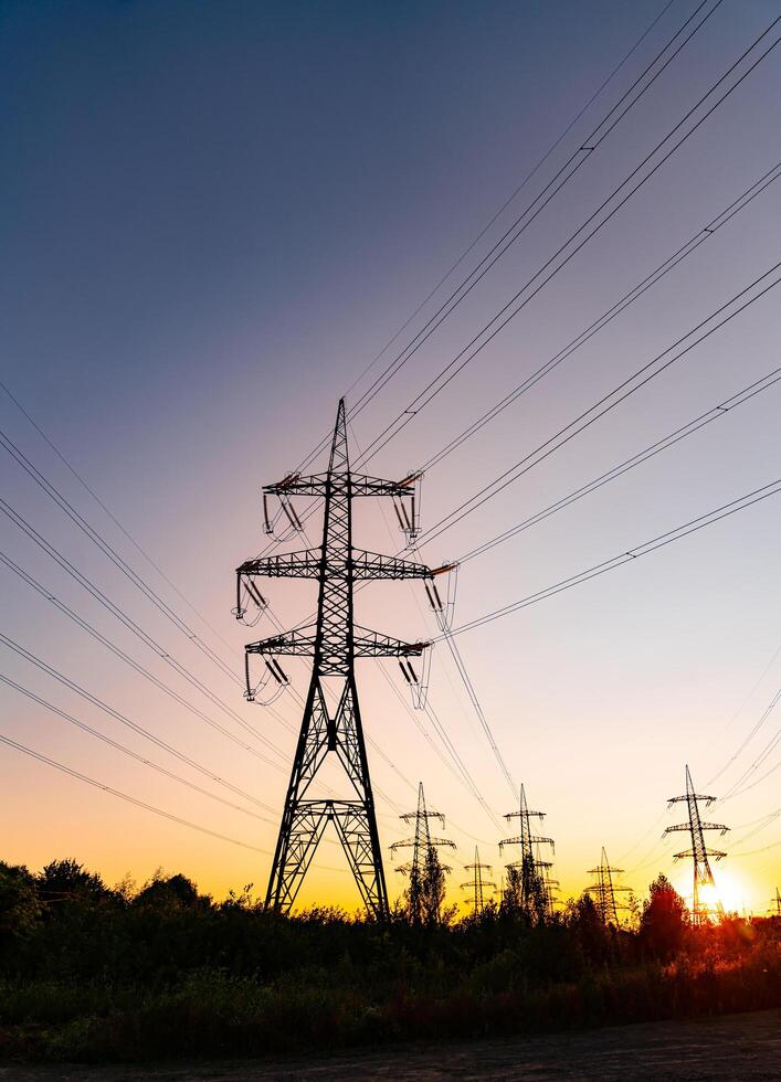 elektricitet kraft station på de bakgrund av blå himmel och miljö Sol. skön landskap av en kraft pylon silhuett och mörkare himmel. foto