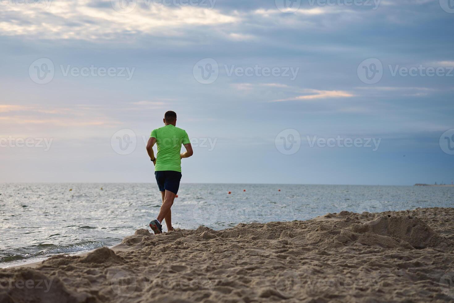 tillbaka se av man joggning längs hav strand på morgon- foto