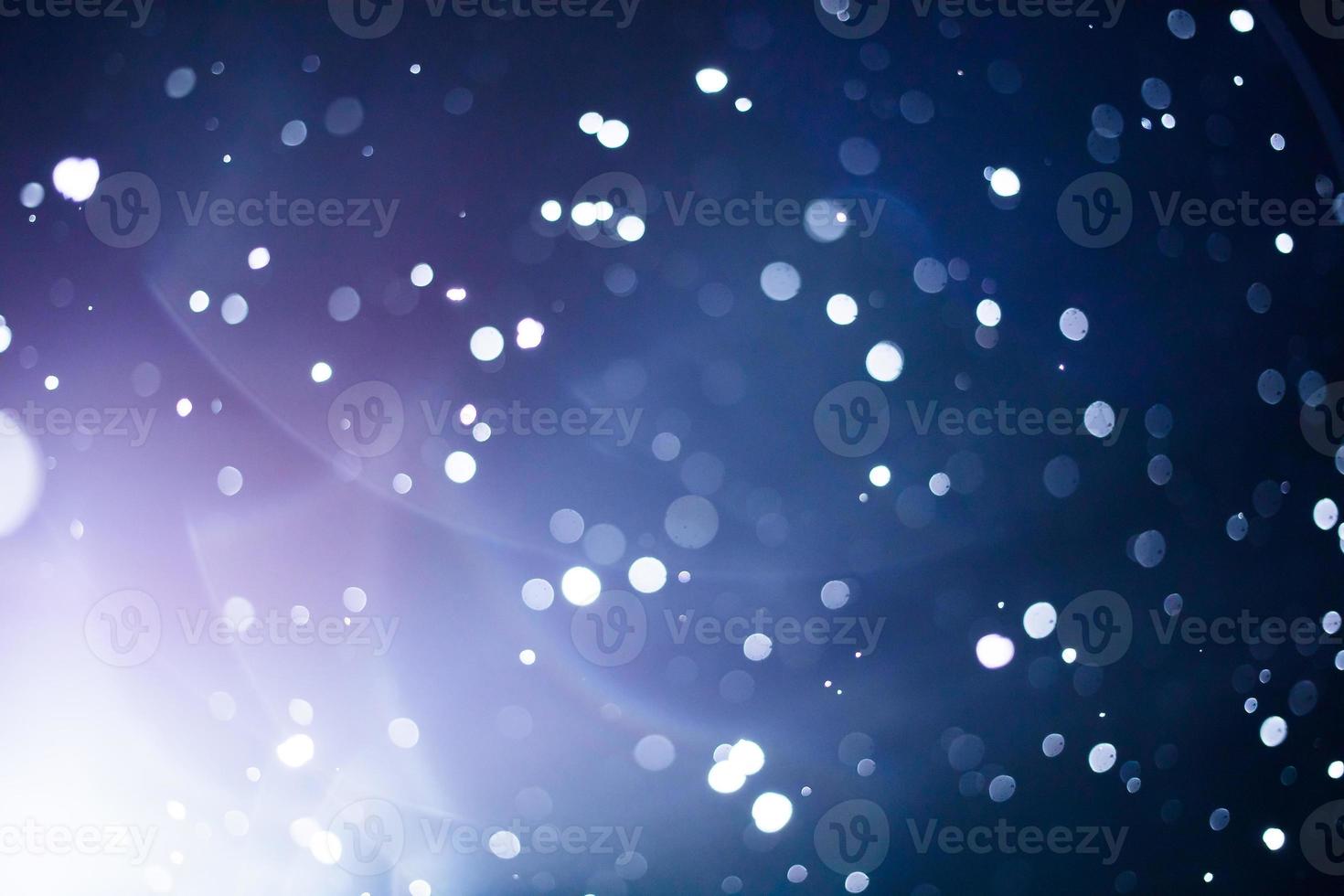 blöta och självgoda linser och suddiga snöflingor under snöstorm på natten foto