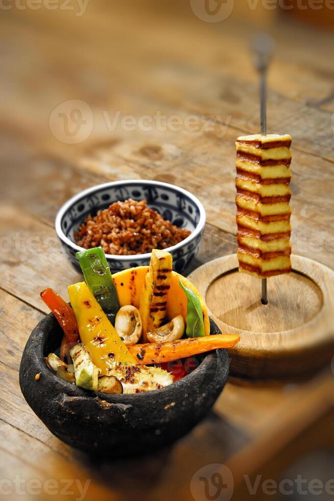 rostad grönsaker med rostad ostmassa ost och röd ris foto