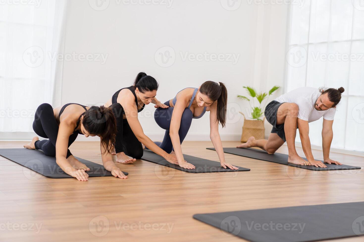 en yoga lärare och henne grupp av studenter do grundläggande yoga poser i en klassrum i en kondition Centrum i de studio. foto