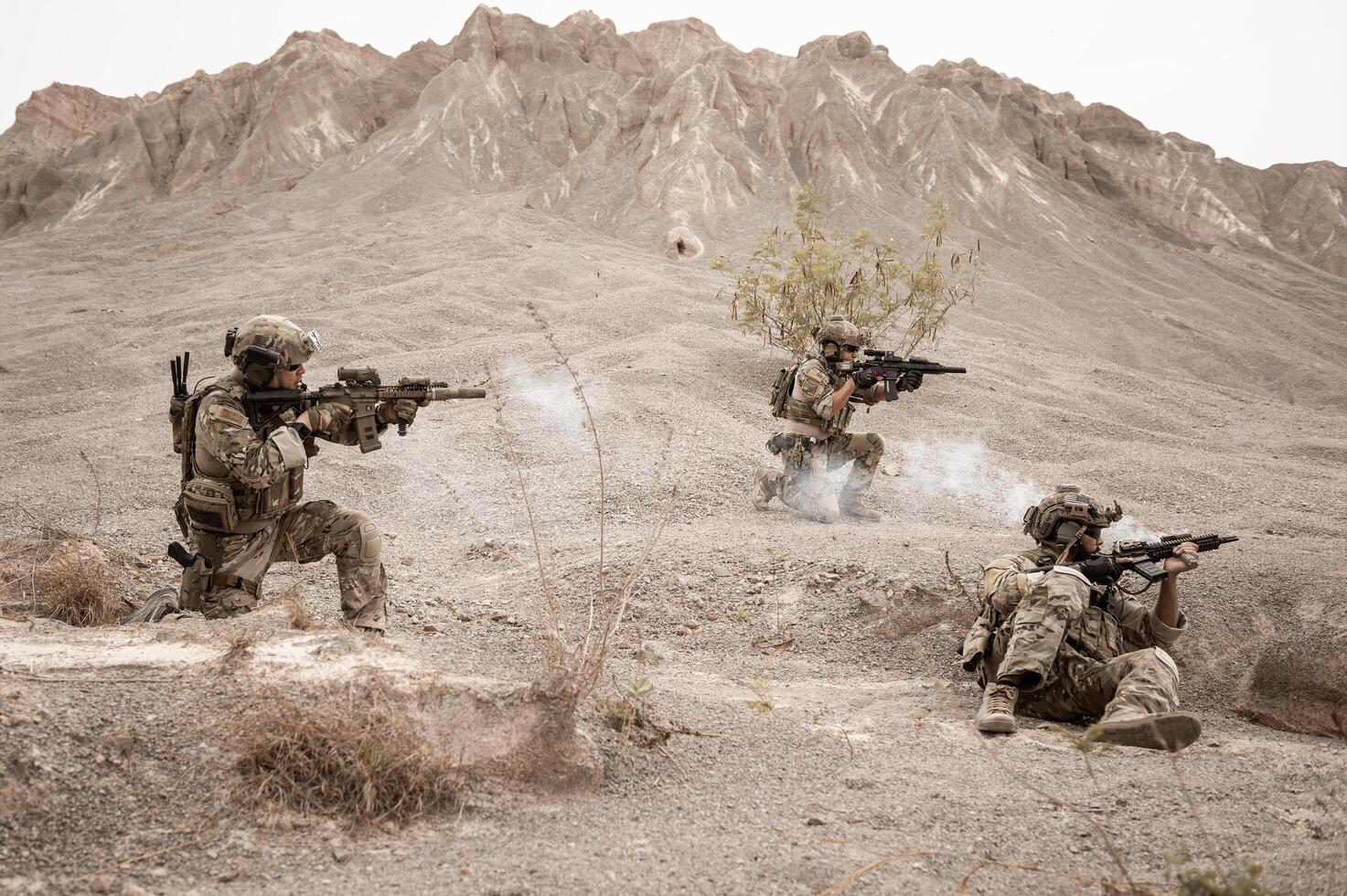 soldater i kamouflage uniformer siktar med deras gevär redo till brand under militär drift i de öken- soldater Träning i en militär drift foto