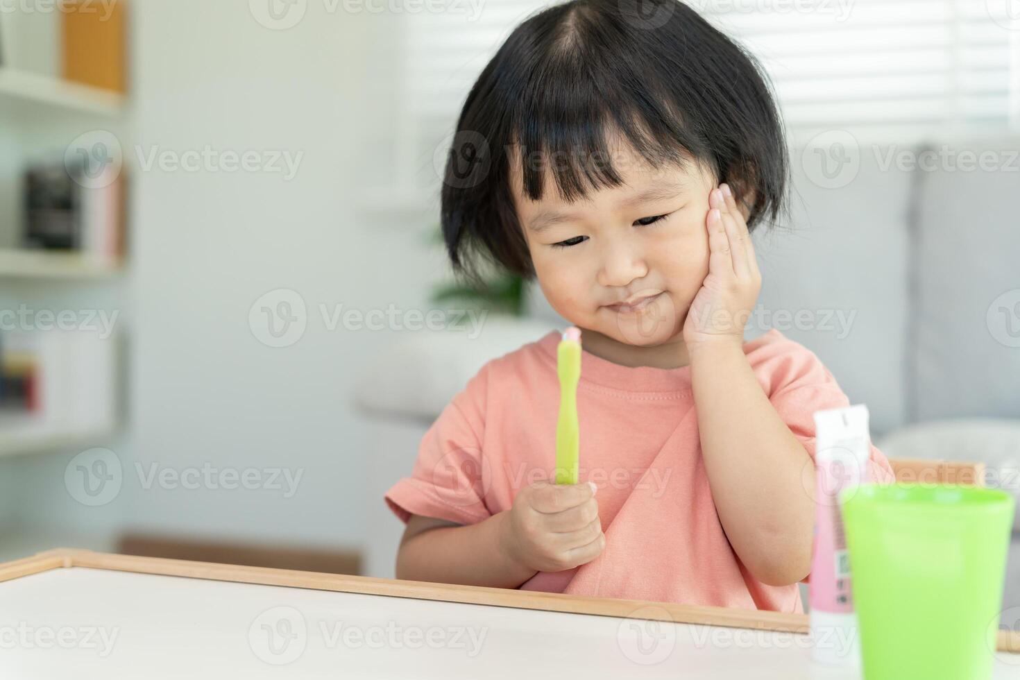 liten asiatisk flicka trycker på hand till kind, lider från smärta i tand. tänder förfall, dental problem, barn känslor och ansiktsbehandling uttryck, oral hälsa vård, minska sötsaker, fluor beläggning foto