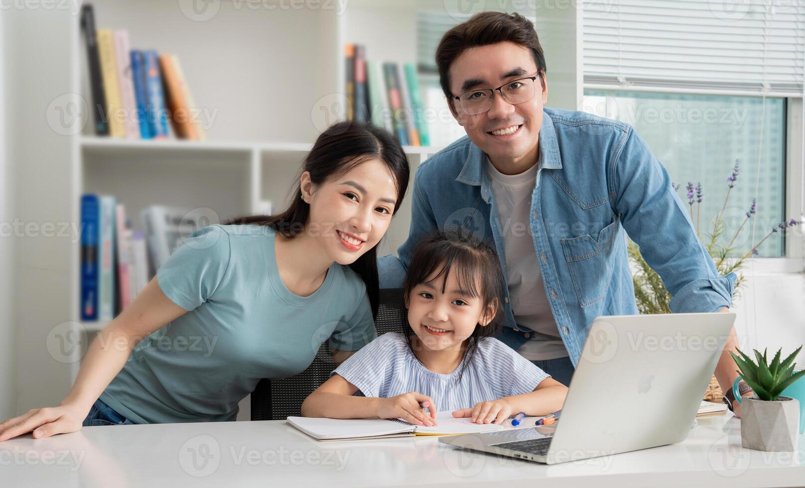 Foto av ung asiatisk familj studerar tillsammans på Hem