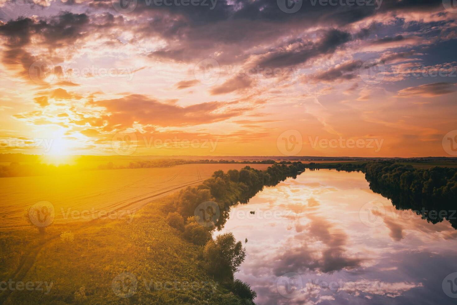 en solnedgång eller soluppgång scen över en sjö eller flod med molnig himmel reflekterande i de vatten på en sommar kväll eller morgon. estetik av årgång filma. foto