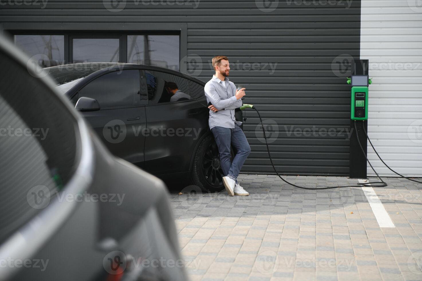 en man står nära en laddning station och kostnader hans elektrisk bil foto