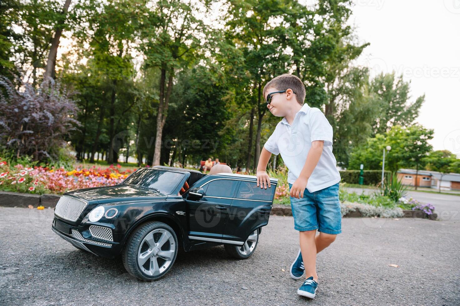 söt pojke i ridning en svart elektrisk bil i de parkera. rolig pojke rider på en leksak elektrisk bil. kopia Plats. foto