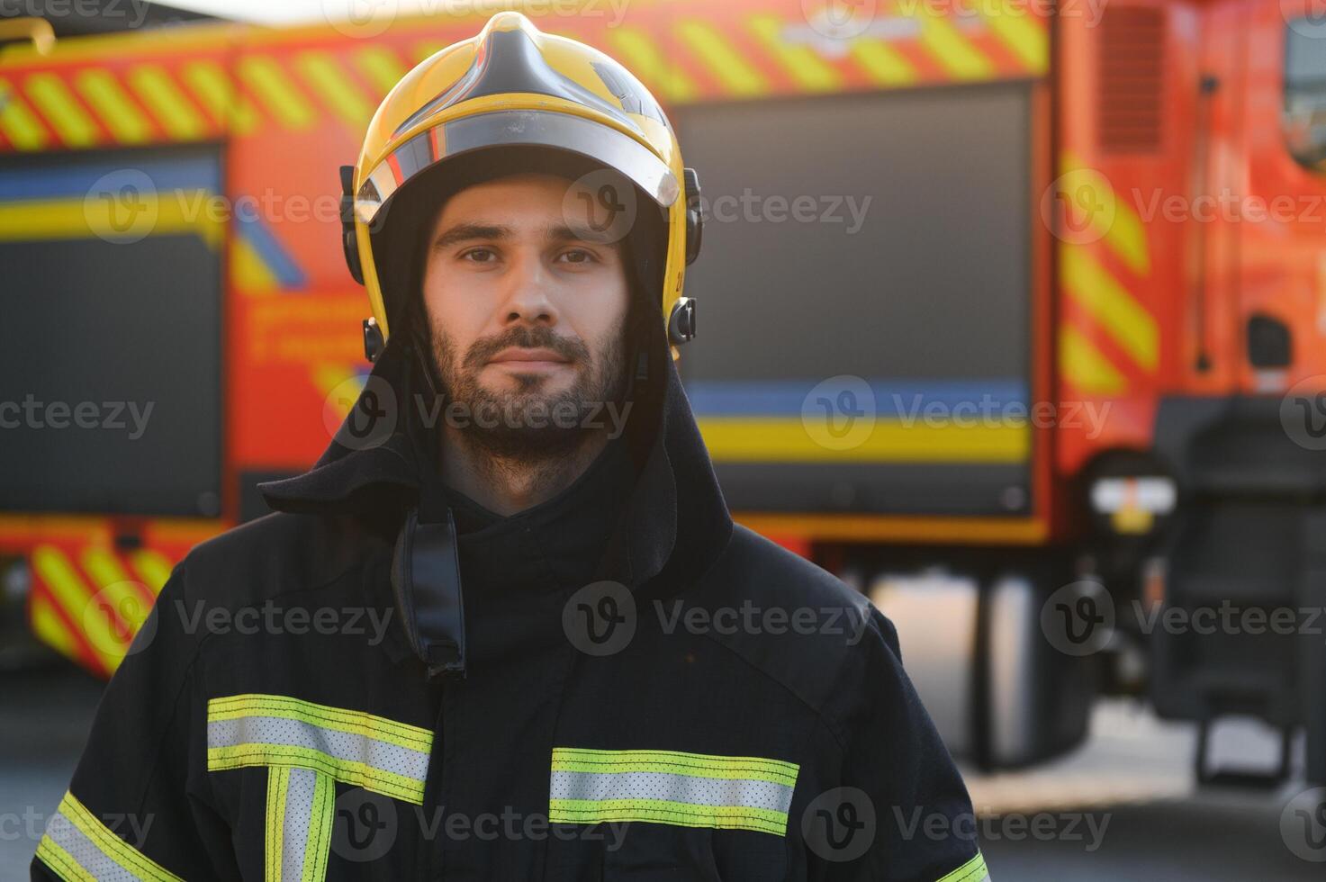 brandman i skyddande enhetlig stående nära brand motor på station foto