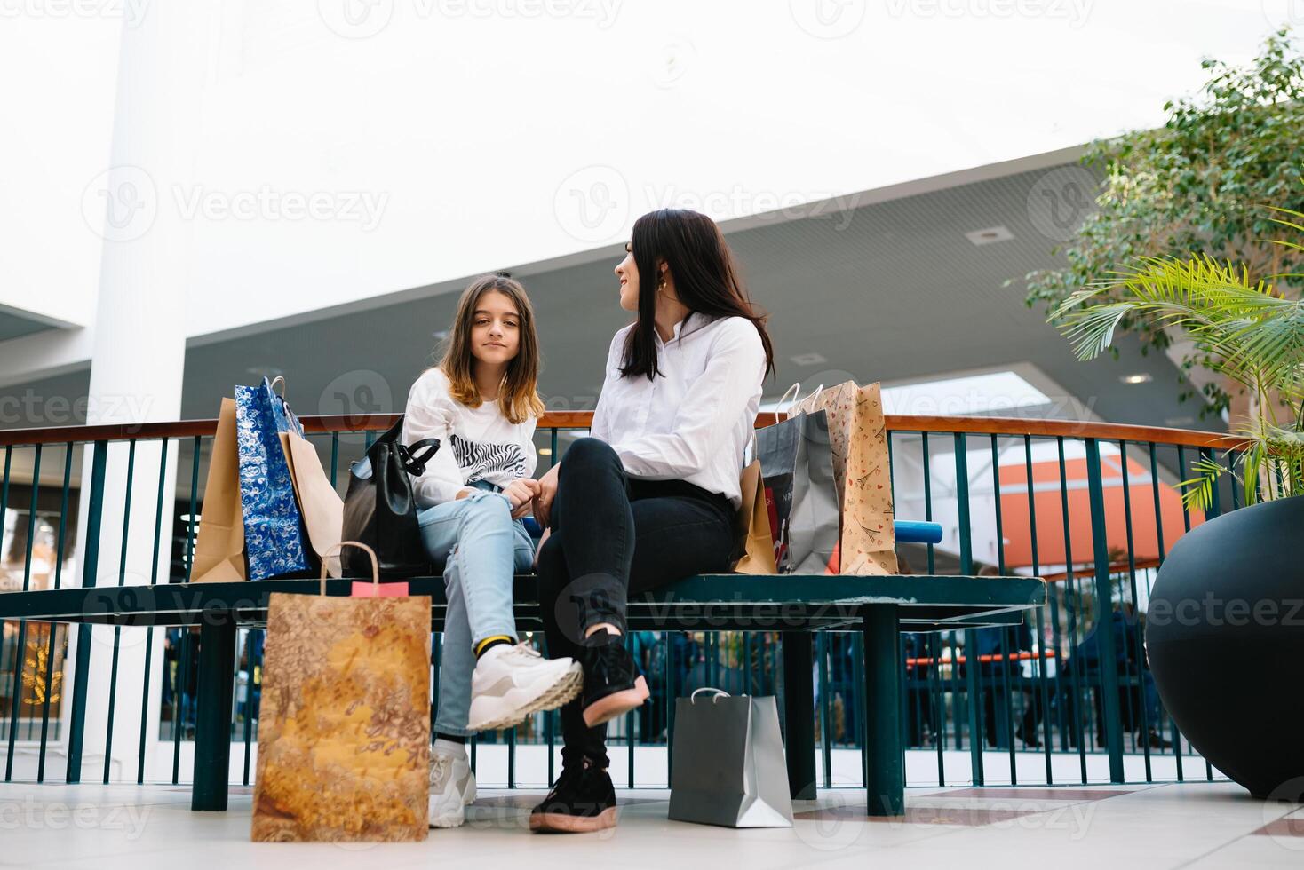 skön ung mamma och Tonårs dotter är innehav handla påsar, handla i köpcenter. familj handla. foto