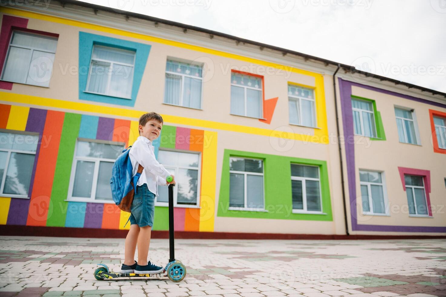 pojke går till skola på en skoter. barn tillbaka till skola skoter.barnskola ridning en skoter. tillbaka till skola. Lycklig barn. Lycklig barndom livsstil. studerande går till skola foto