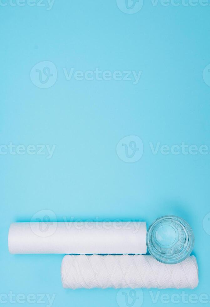 vatten filter. kol patroner och en glas med vatten på en blå bakgrund. hushåll filtrering systemet foto