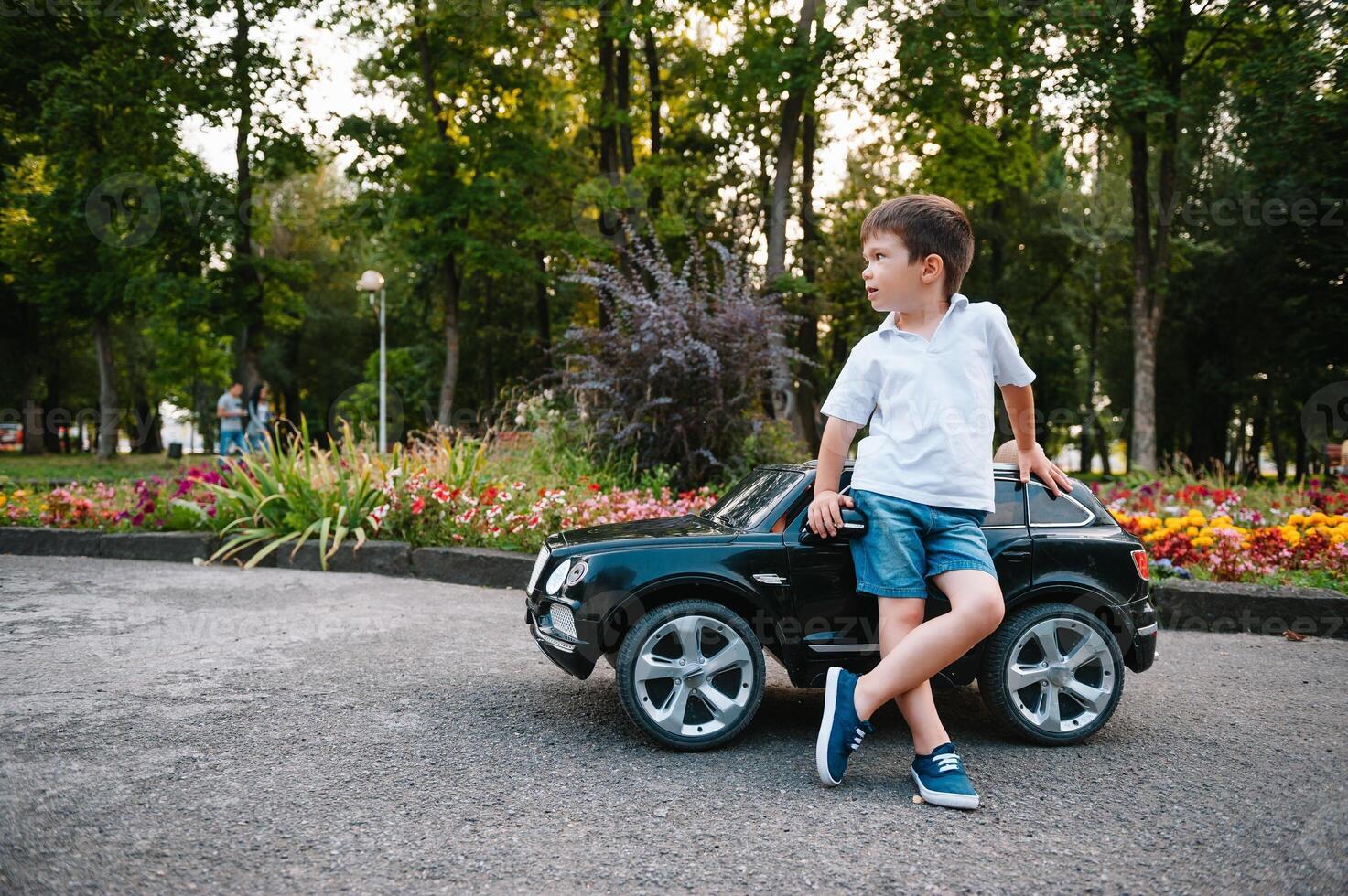 söt pojke i ridning en svart elektrisk bil i de parkera. rolig pojke rider på en leksak elektrisk bil. kopia Plats. foto