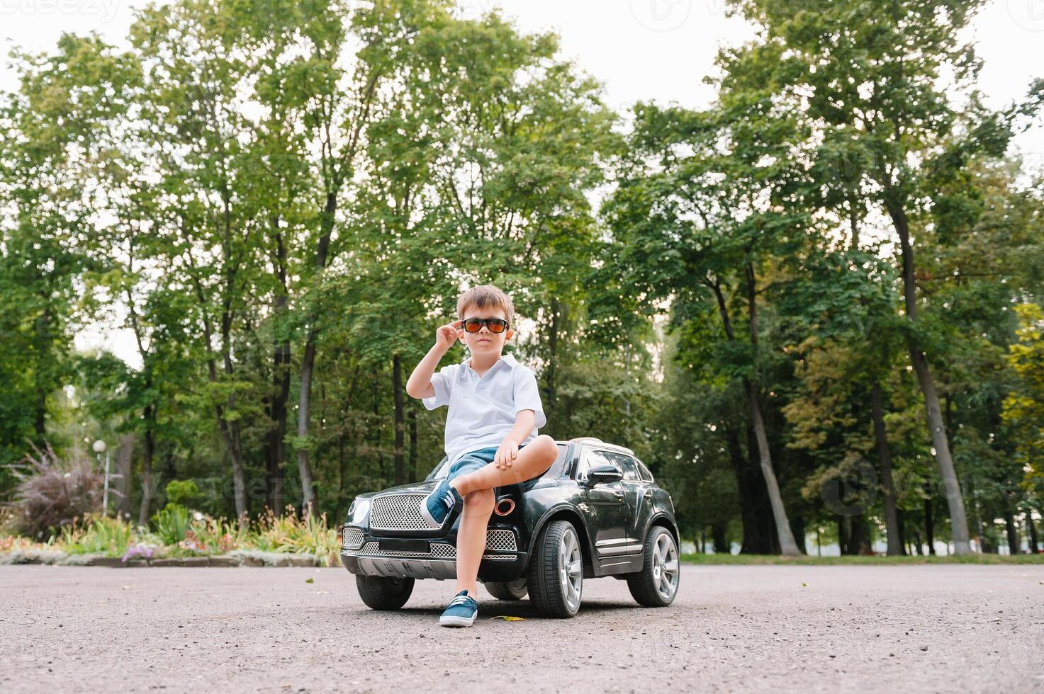 söt pojke i ridning en svart elektrisk bil i de parkera. rolig pojke rider på en leksak elektrisk bil. kopia Plats. foto