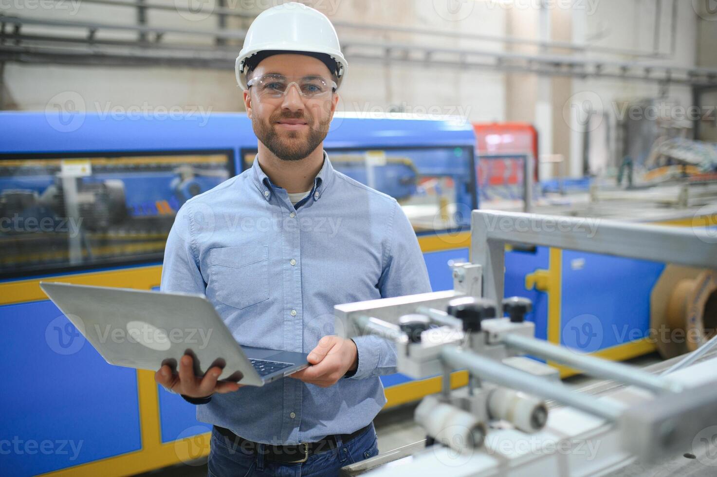 ingenjör i Hardhat är använder sig av en bärbar dator i en tung industri fabrik foto