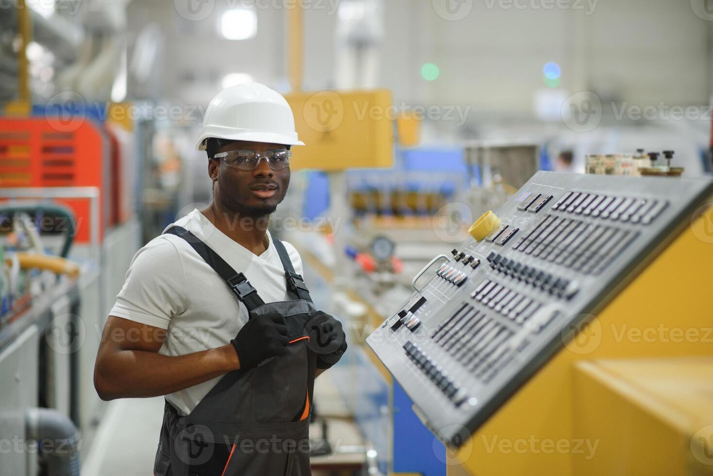 porträtt av industriell ingenjör. leende fabrik arbetstagare med hård hatt stående i fabrik produktion linje foto