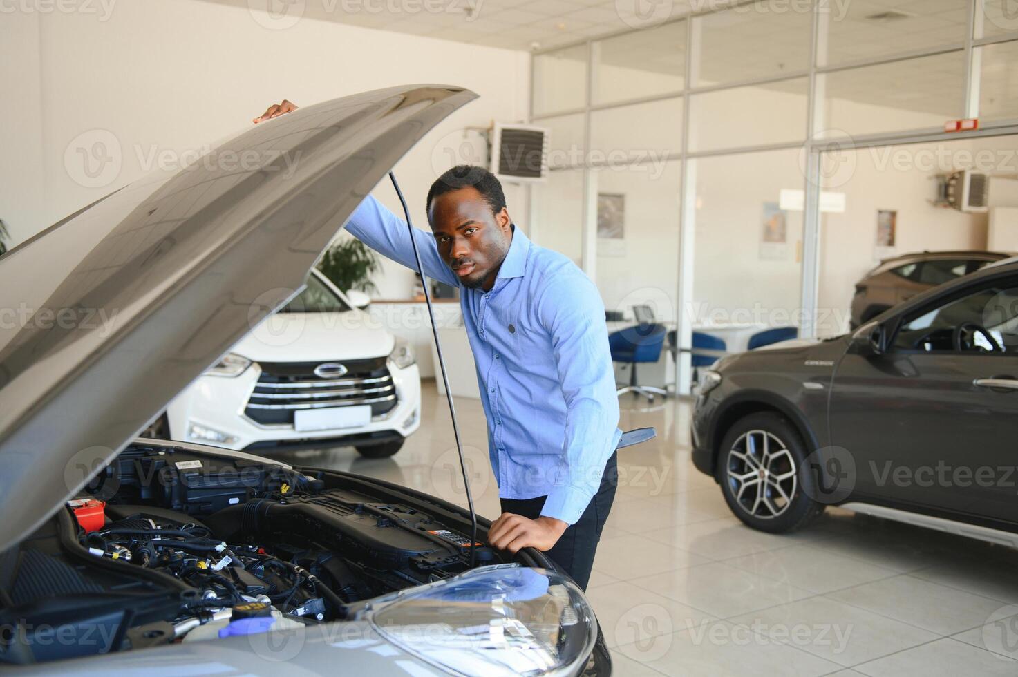 stilig afrikansk affärsman är granskning en bil innan uppköp Det, han checkar Allt egenskaper och funktioner av bil foto