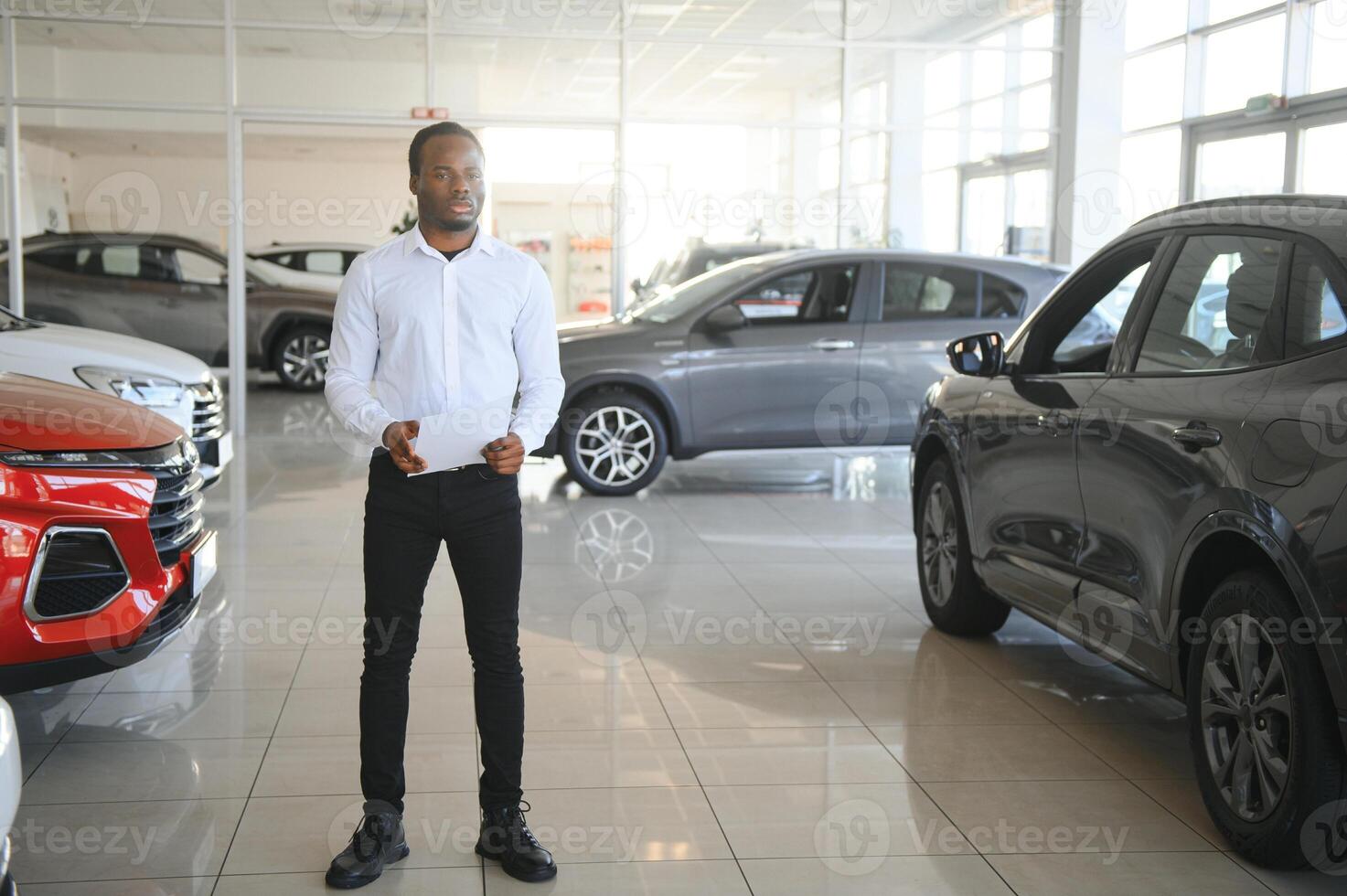 porträtt av stilig afrikansk amerikan försäljare på arbetsplats i bil utställningslokal foto