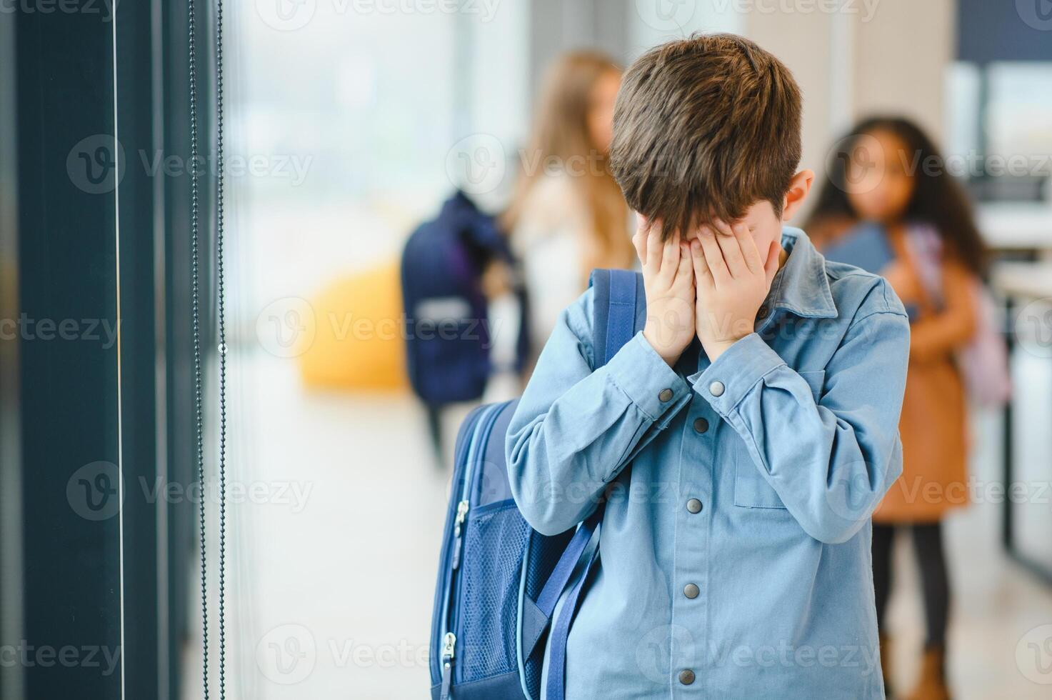 upprörd pojke på skola beläggning hans ansikte med hans händer. mobbning på skola foto