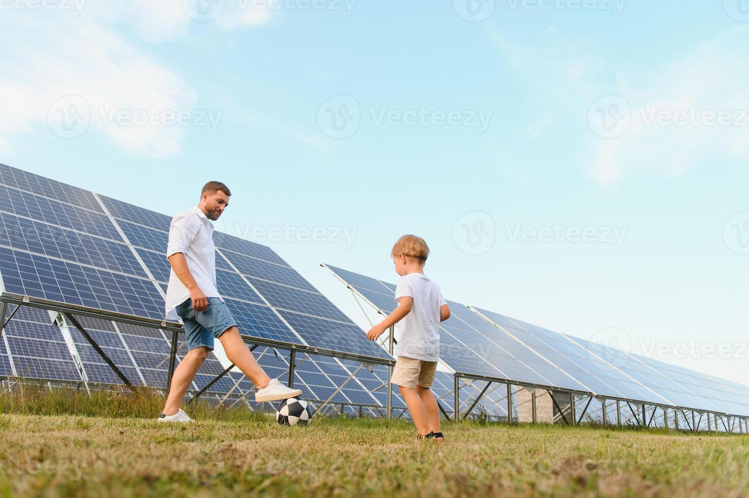 en far och hans liten son spela fotboll nära de sol- paneler. de begrepp av förnybar energi. foto