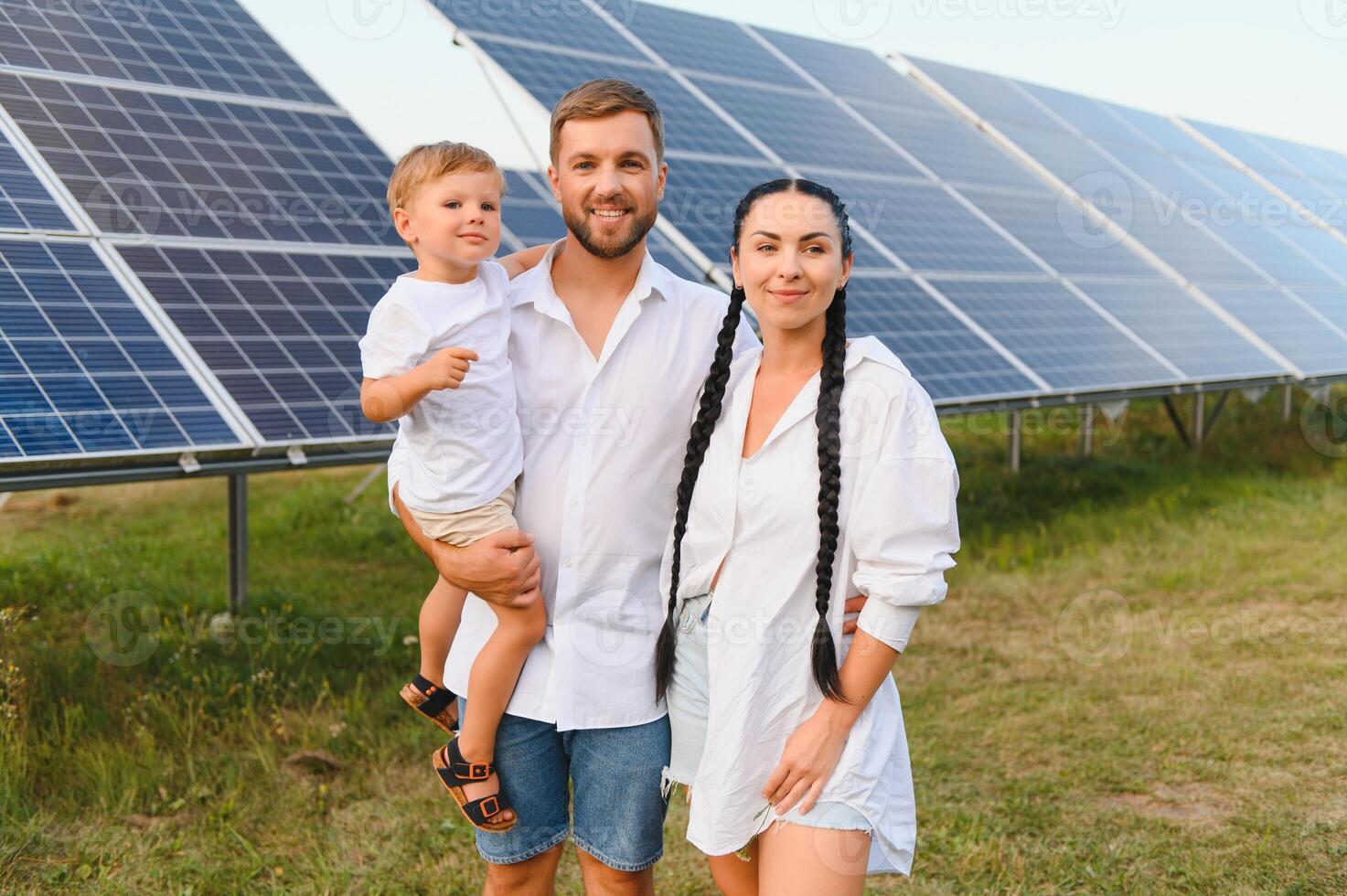 ung familj av tre är hukande nära solceller sol- panel, liten pojke och föräldrar. modern familj begrepp. de begrepp av grön energi foto