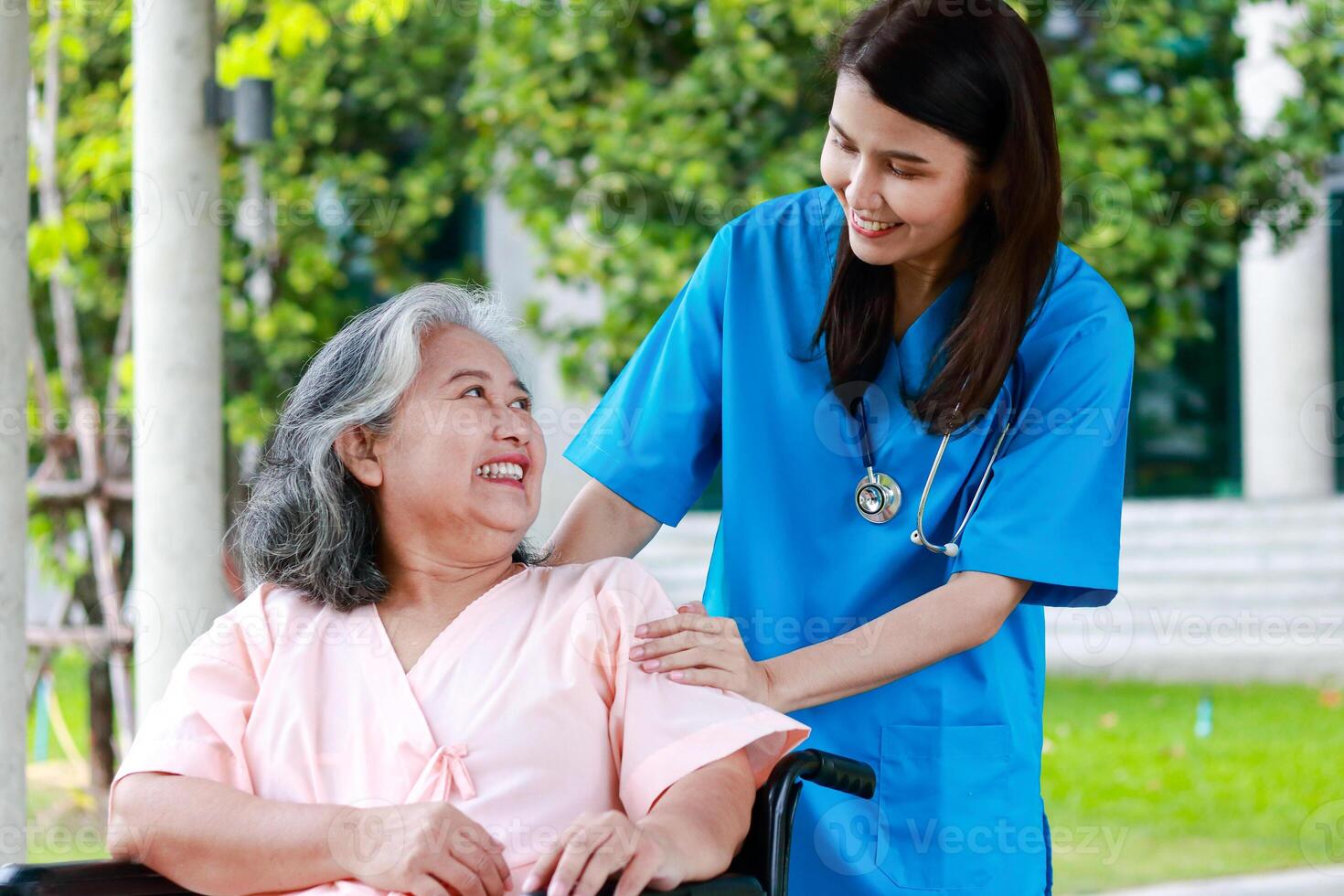 asiatisk kvinna läkare bär kirurgisk klänning rörande de ärm av ett äldre patient Sammanträde på en rullstol uppmuntrande, do inte oroa handla om behandling. begrepp av medicinsk tjänster i sjukhus. foto
