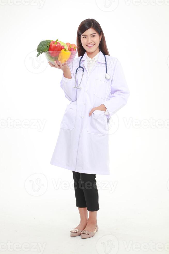 skön ung asiatisk kvinna läkare har en skön leende. innehav en skål av färsk organisk grönsaker mat för Bra hälsa. recept mat näring begrepp, friska äter. vit bakgrund. foto
