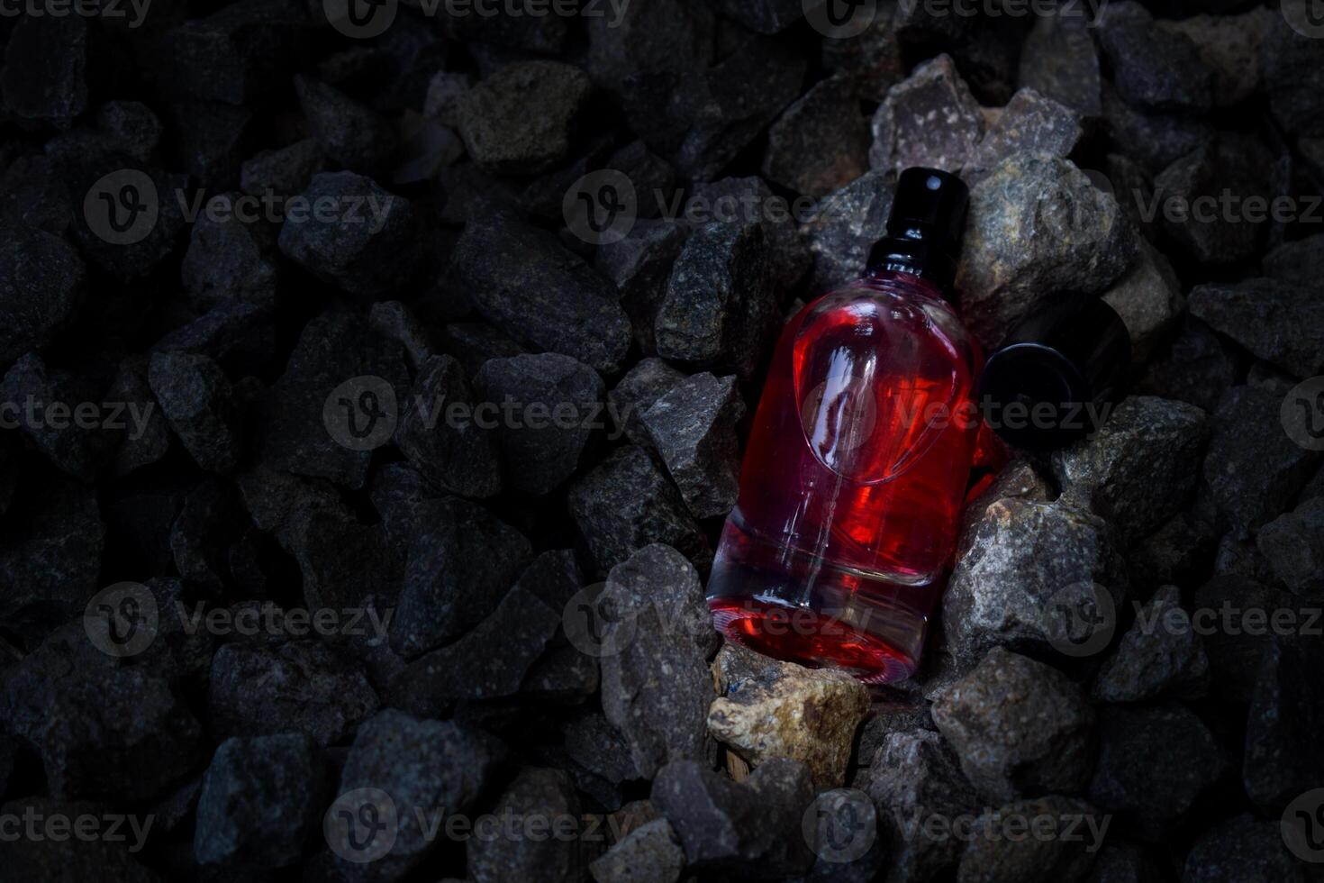 parfym röd transparent flaska i grus eller korall bakgrund foto