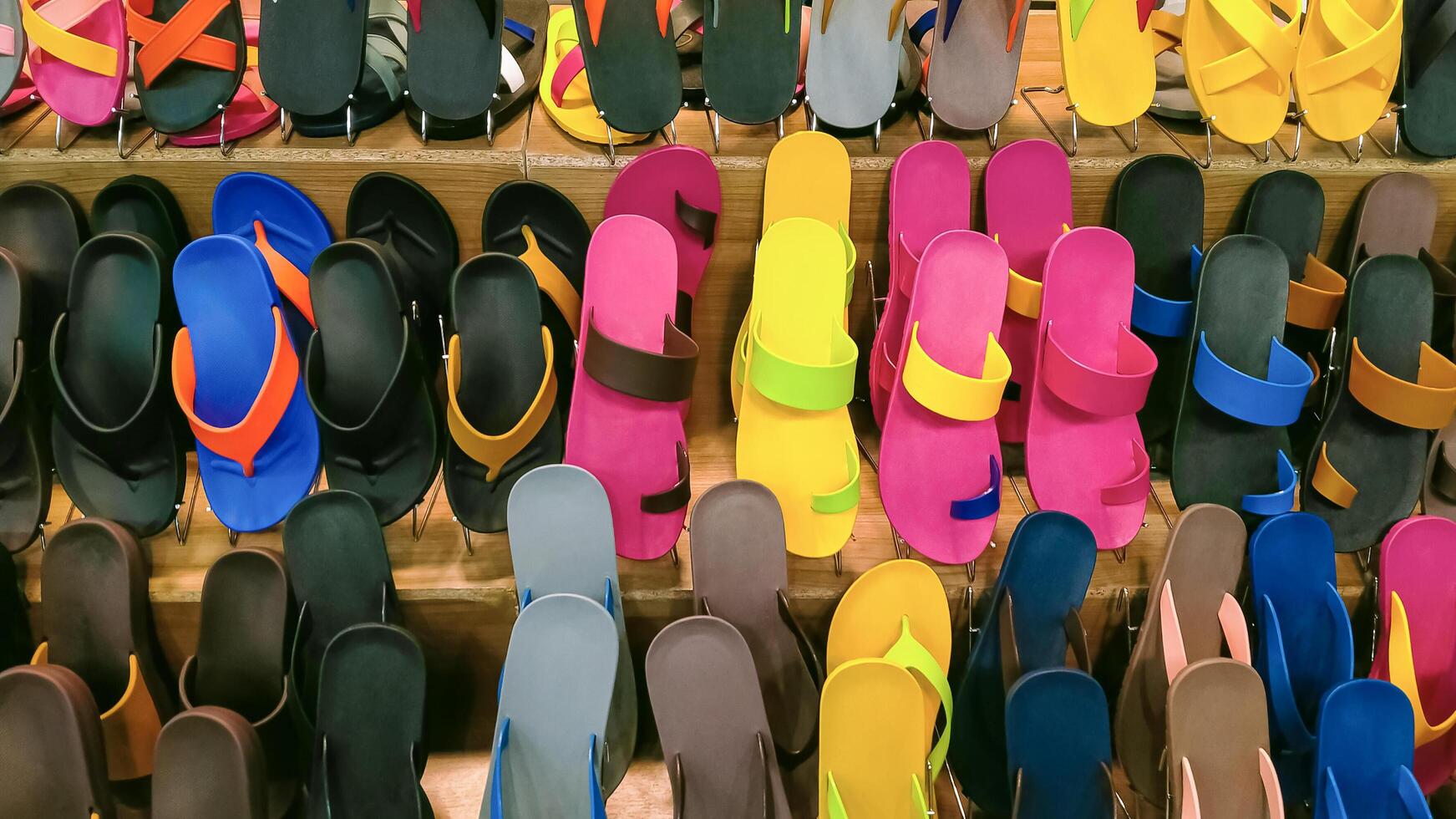 rader av flerfärgad sudd sandaler och flip flops på trä- hylla visa för försäljning i handla köpcenter foto