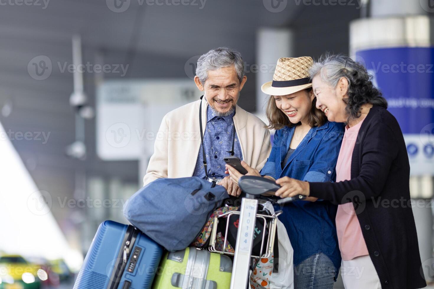 grupp av asiatisk familj turist passagerare med senior är använder sig av mobil Ansökan till ring upp plocka upp taxi på flygplats terminal för transport under de semester resa och lång helgen Semester foto