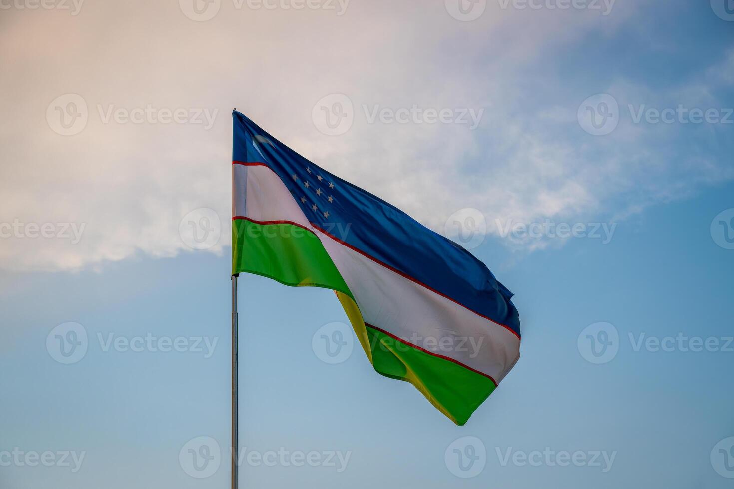 flagga av uzbekistan vinka på en solnedgång eller soluppgång dramatisk himmel bakgrund. foto