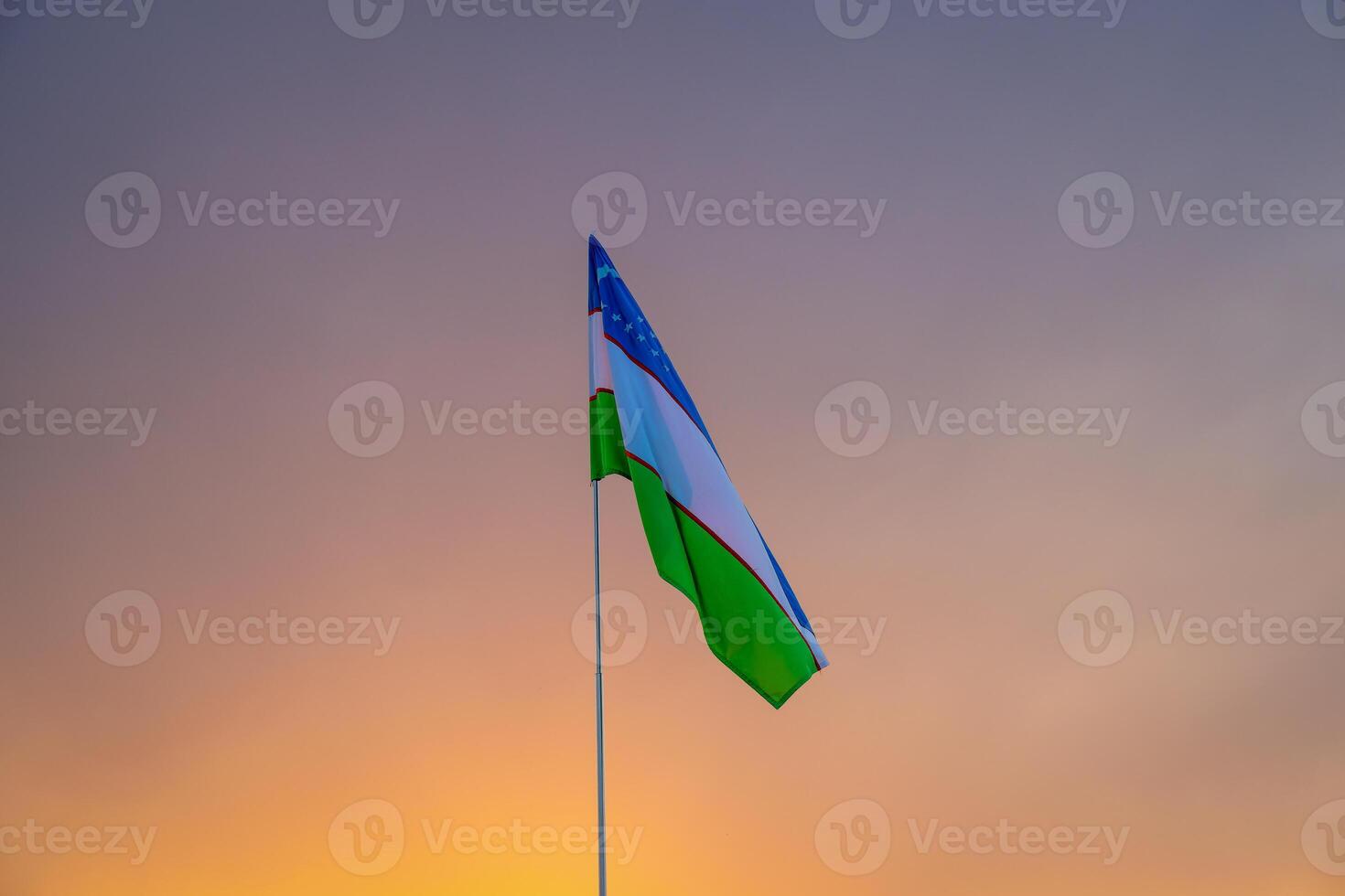 flagga av uzbekistan vinka på en solnedgång eller soluppgång dramatisk himmel bakgrund. foto