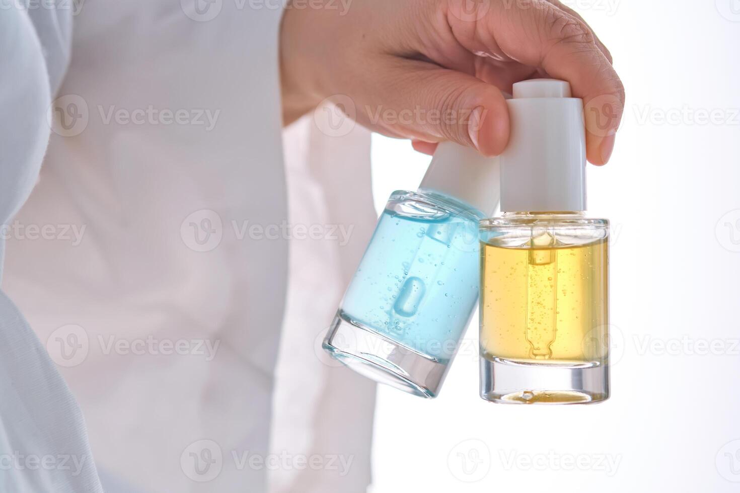 två gul och blå serum i en kvinnors händer i en morgonrock. foto