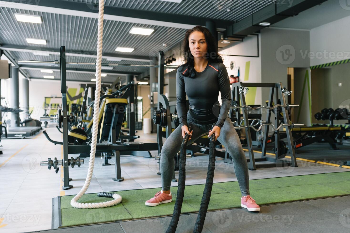 Söt latinamerikan ung kvinna håller på med några crossfit övningar med en rep på en Gym. foto