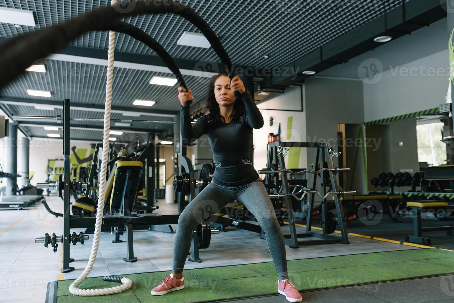 Söt latinamerikan ung kvinna håller på med några crossfit övningar med en rep på en Gym. foto