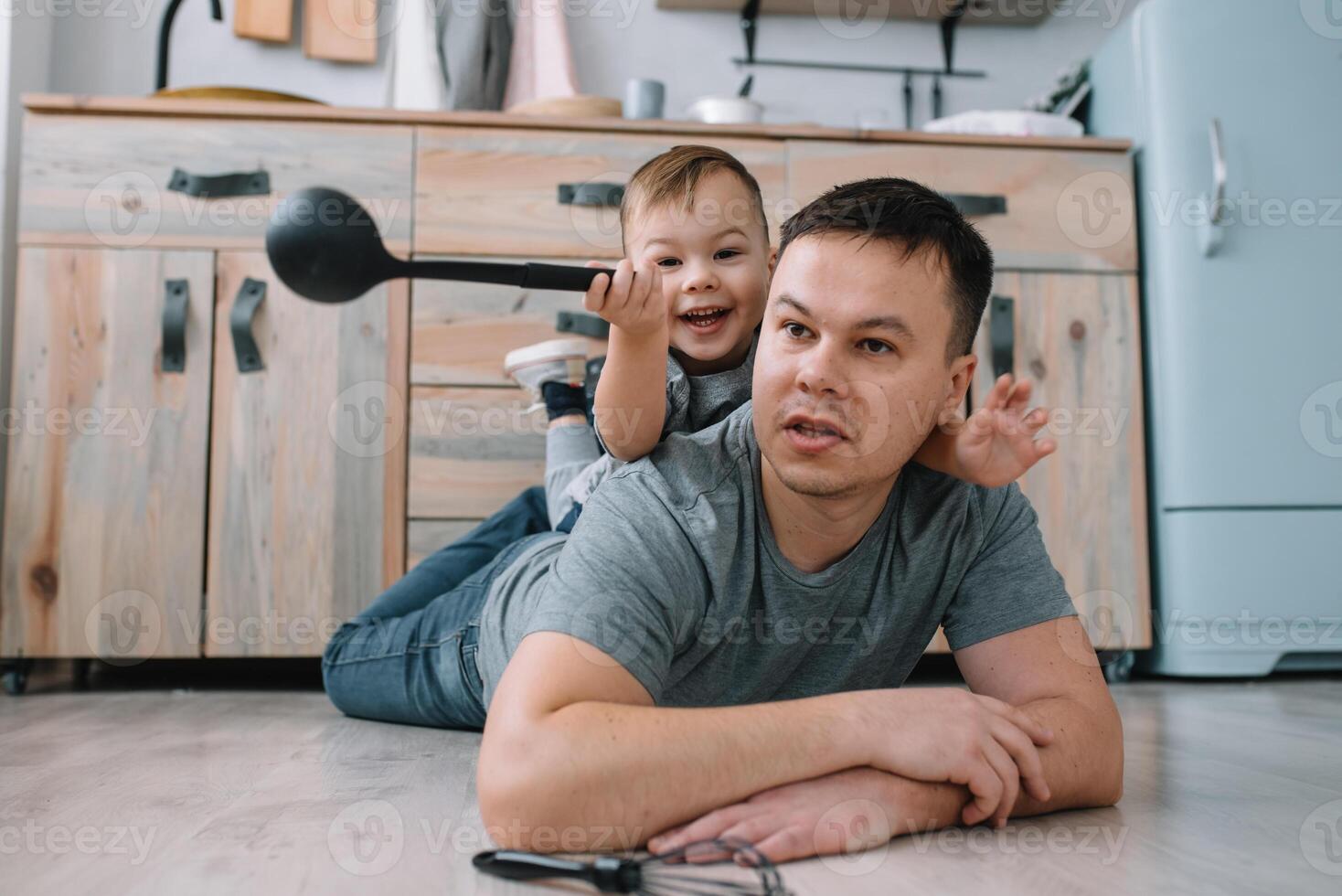 ung man och hans son med ugn ark i kök. far med liten son på de kök foto