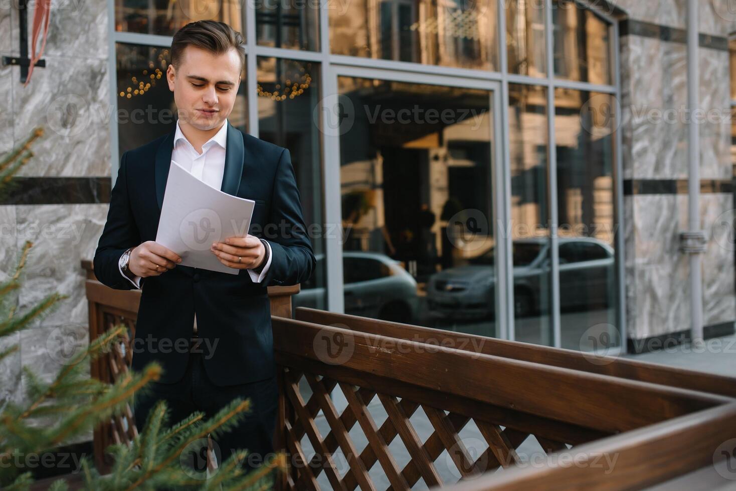 ung företag man med dokument och mobil telefon nära av modern byggnad. foto