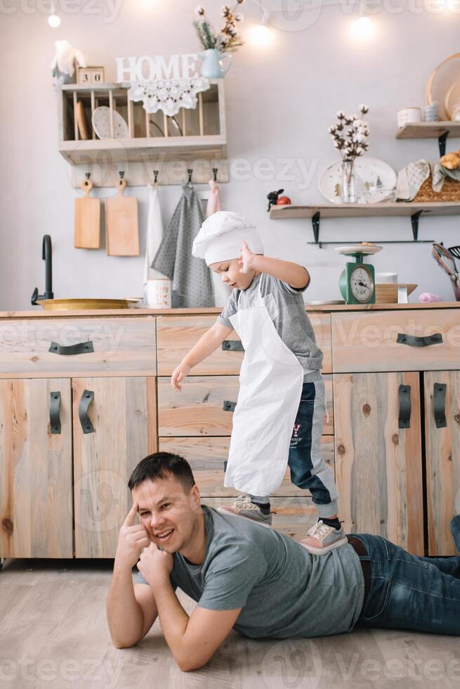 ung man och hans son med ugn ark i kök. far med liten son på de kök. foto