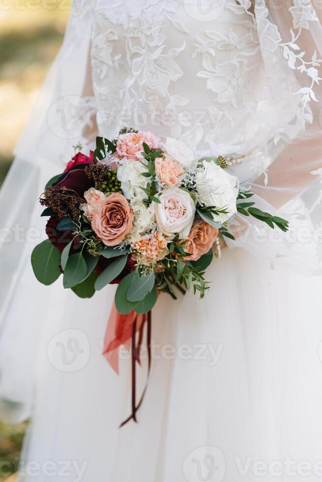 brud står i en vit bröllop klänning med en bukett av blommor. foto