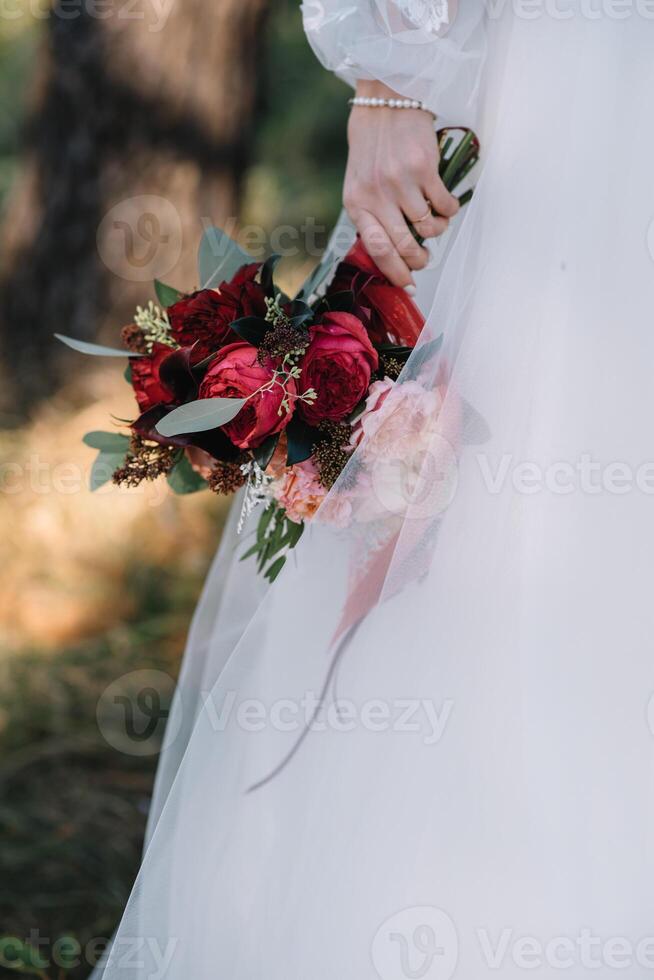 brud står i en vit bröllop klänning med en bukett av blommor. foto