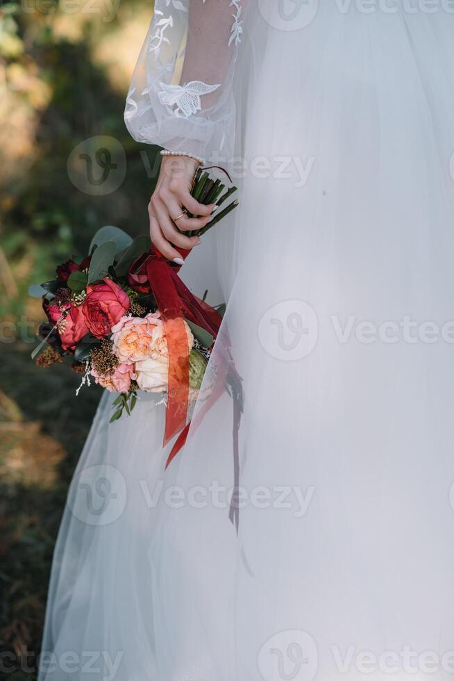 brud står i en vit bröllop klänning med en bukett av blommor foto