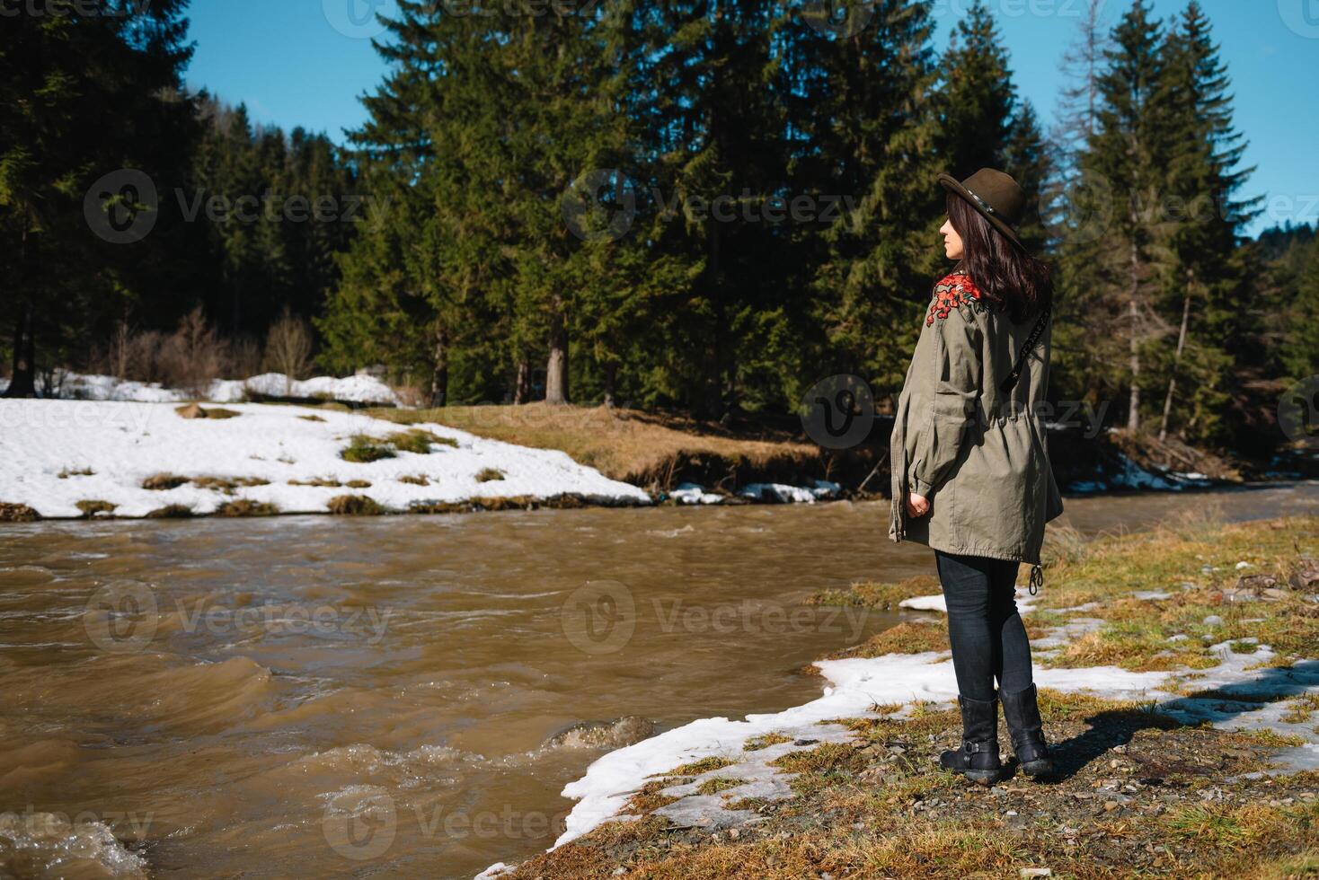 eleganta flicka reser i skogen. ung kvinna i hatt utforska i sommar skog, ser på flod. resa och reslust begrepp. Plats för text. foto