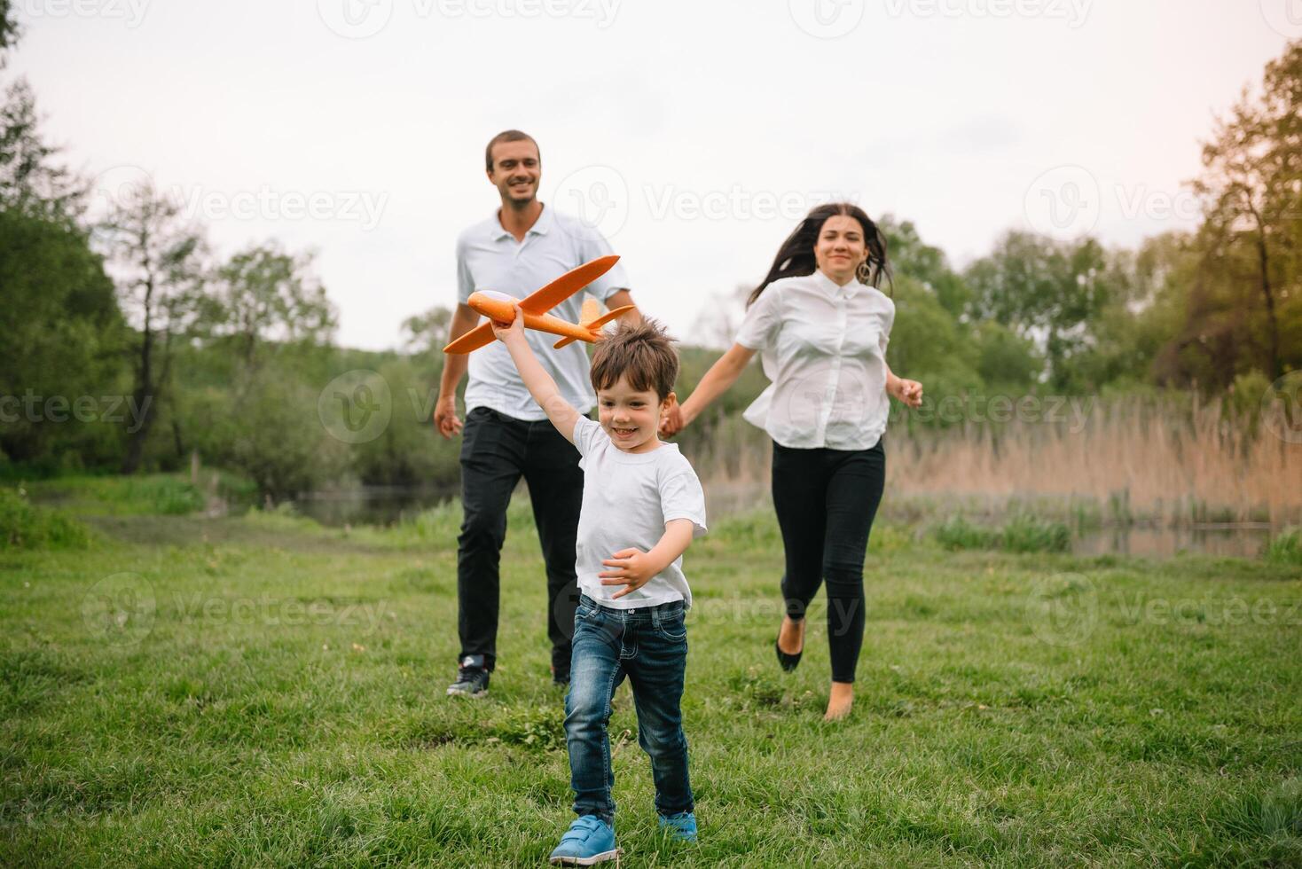 far, mor och son spelar med leksak flygplan i de parkera. vänlig familj. människor har roligt utomhus. bild tillverkad på de bakgrund av de parkera och blå himmel. begrepp av en Lycklig familj. foto